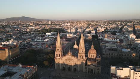 Drone-Aéreo-Vuela-Sobre-Guadalajara-México-Iglesia-Hito-Viaje-Ciudad-Centro-Histórico,-Arquitectura-De-Edificio-Católico-Romano-Al-Atardecer-Alrededor-De-Casas-Tradicionales-Locales