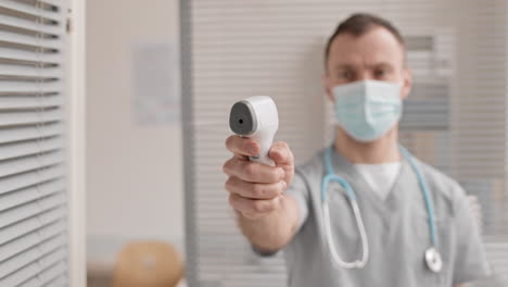 médico borroso con termómetro infrarrojo