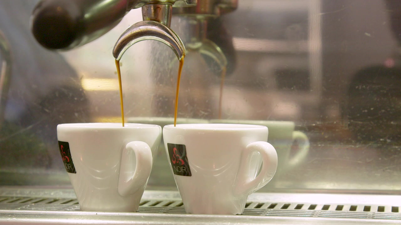 Come fare un vero espresso italiano: filmato di caffè che gocciola in due tazzine da espresso in un bar