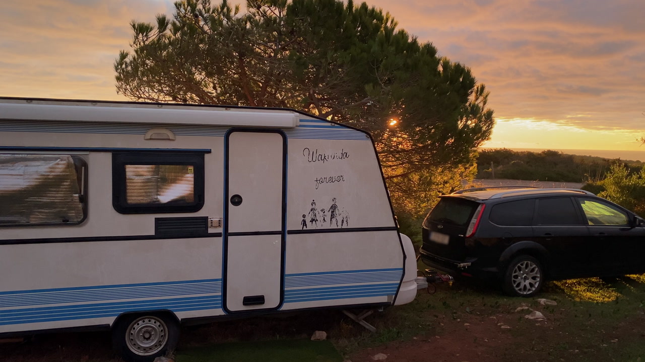Caravan parked in the wild Algarve landscape near Zavial Beach during golden hour, capturing a slow travel lifestyle surrounded by nature and Atlantic light