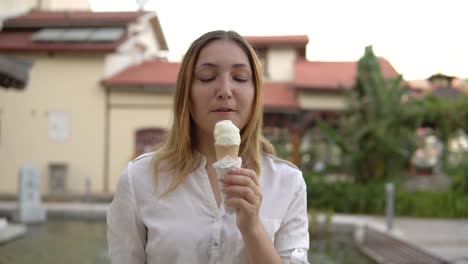 retrato de una hermosa joven positiva comiendo helado en el fondo de las palmeras