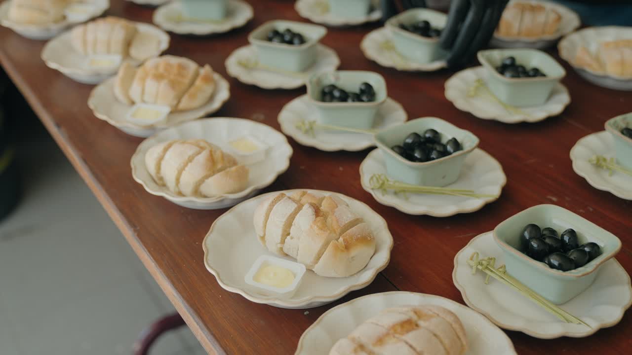 Sliced bread with butter and black olives arranged on plates for a meal in Portugal