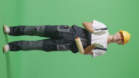 full body of asian man painter wearing safety helmet smiling and clapping his hands while standing in the green screen background studio