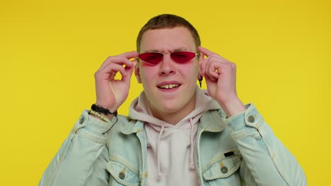 un hombre alegre y feliz con gafas de sol parpadeando los ojos mirando a la cámara con una sonrisa guiñando el ojo y coqueteando