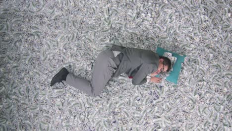 a businessman man sleeps against the background of banknotes on a pillow top view