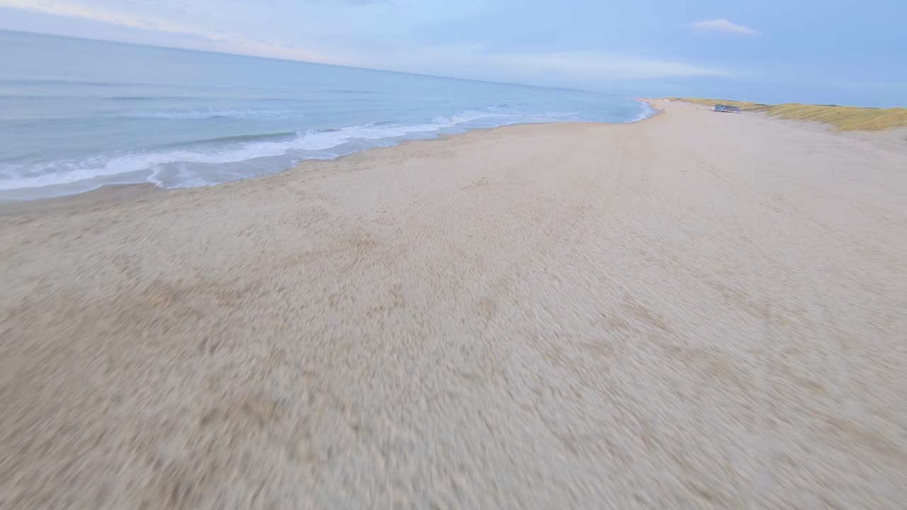Fast drone shot following the empty beach of Oostkapelle away from the sunset