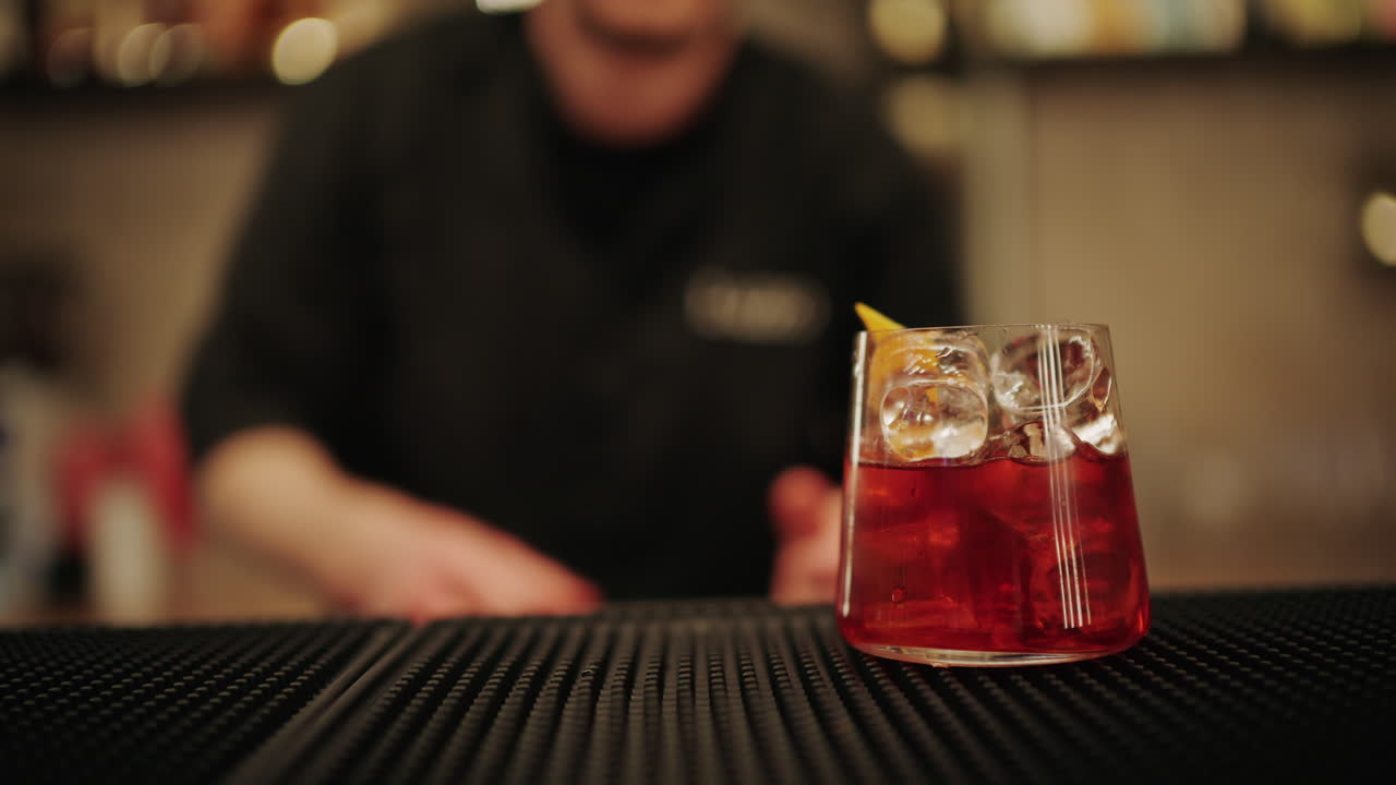Primo piano di mani che spremono limone fresco in un bicchiere da cocktail con ghiaccio
