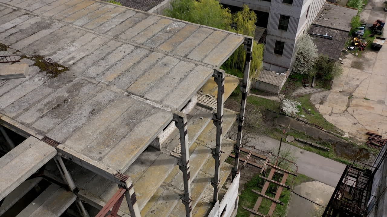 Unfinished building of abandoned factory. Old industrial architecture in spring. Camera rising. Aerial view.