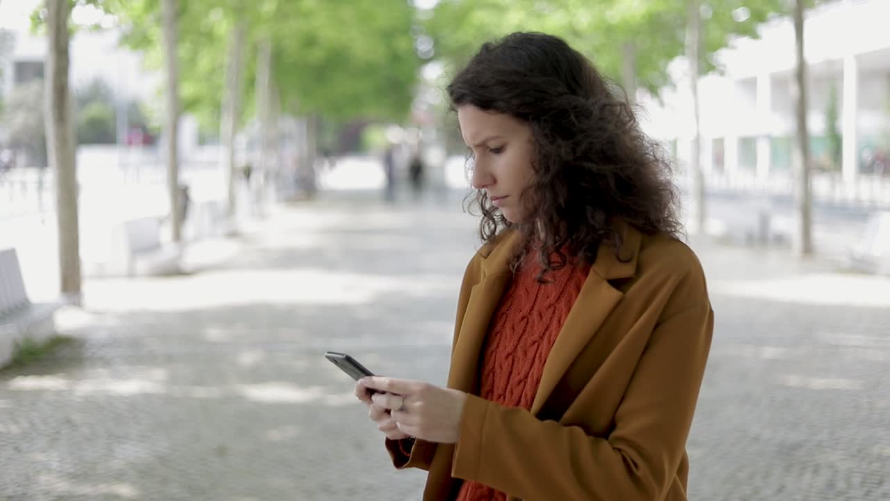 Giovane donna seria che usa lo smartphone all'aperto