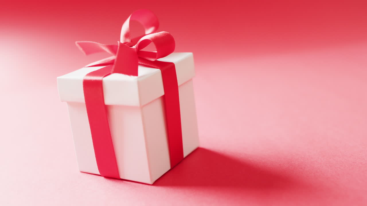 video de corbatas blancas de caja de regalo con cinta roja, sobre fondo rojo, con espacio para copiar