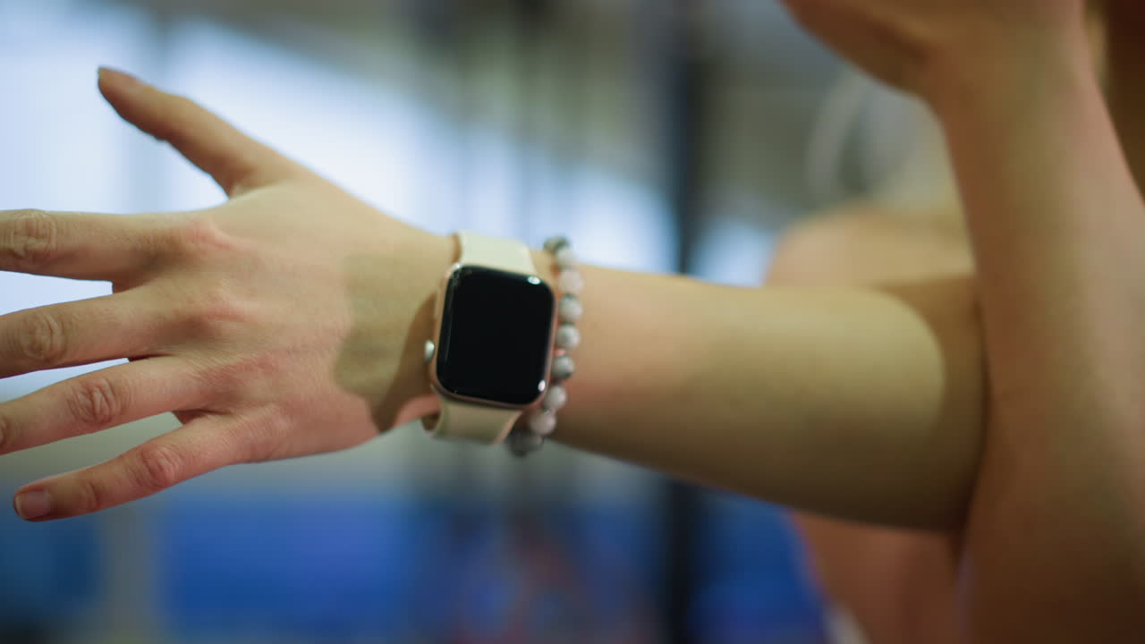 Closeup caucasian woman hand with watch and chalky fingers preparing for lift in gym, wearable device on wrist with beaded bracelet, tense grip and knuckles, detailed skin texture, blurred equipment