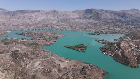 aerial view descending towards woodland island in the middle of green lake in the taurus mountains of turkey