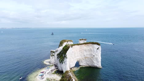 aerial tilt down of rock formation and sea kayaks on sunny day, old harry rocks, uk