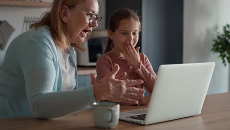 Abuela-Y-Nieta-Caucásicas-Usando-Una-Computadora-Portátil-En-La-Cocina