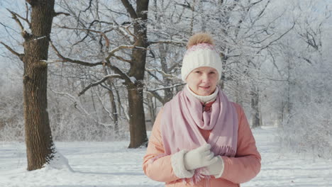 kobieta w średnim wieku spaceruje po parku zimowym w pogodny dzień, pada śnieg, wideo w zwolnionym tempie 4k