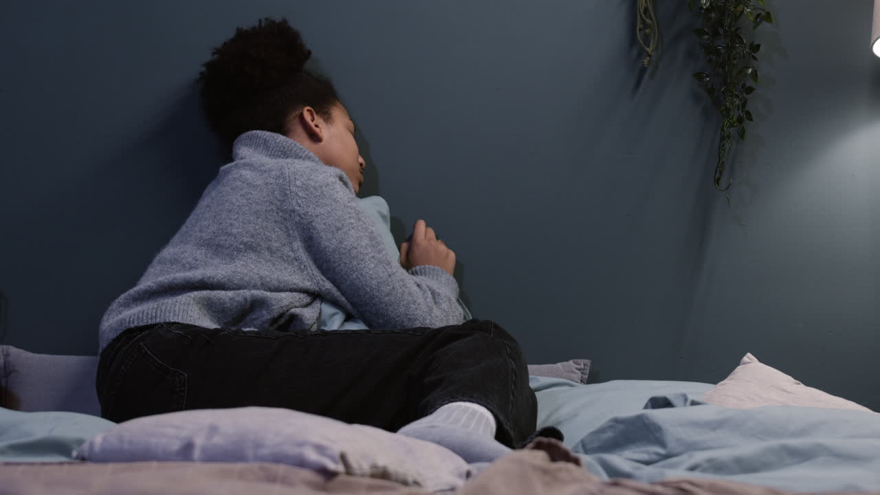 uma mulher infeliz a abraçar uma almofada na cama.