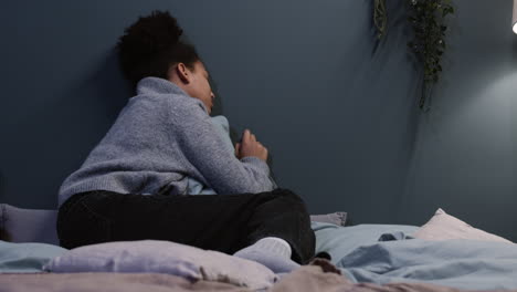 mujer infeliz abrazando una almohada en su cama
