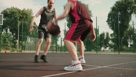 un hábil jugador de baloncesto botando el balón entre las piernas contra su defensor contrario en una cancha de baloncesto al aire libre