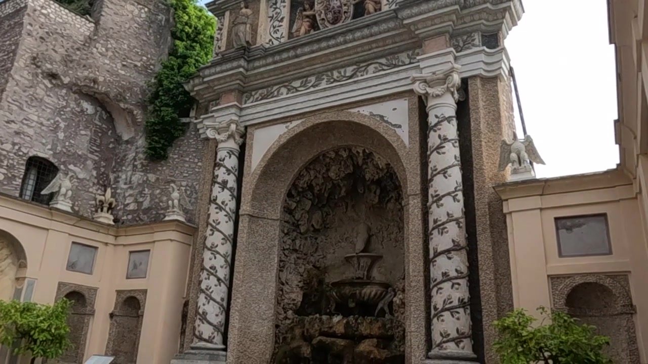 Panorâmica lenta pela elaborada fachada de igreja barroca apresentando alvenaria decorativa, arco esculpido e cruz.