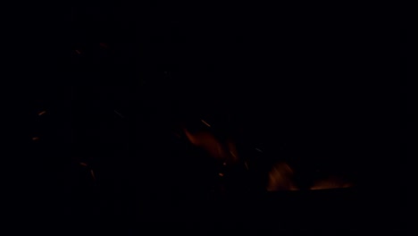 chispas ardientes y calientes surgen de un gran fuego en el cielo nocturno, en cámara lenta.