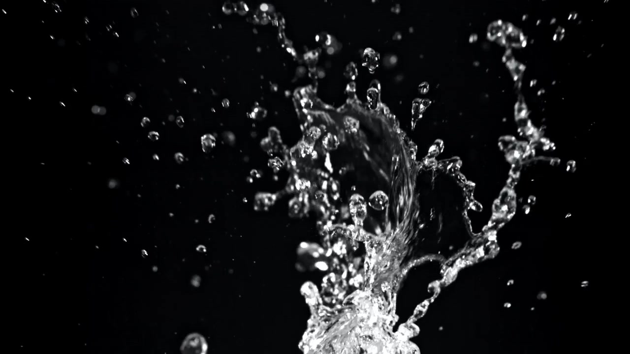 Klart vand sprøjter opad i slowmotion på sort baggrund