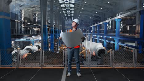 full body of asian male engineer with safety helmet looking at blueprint in his hands and looking around while standing in factory manufacture of wind turbines