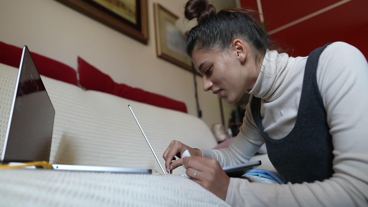 Young woman working from home on laptop and tablet