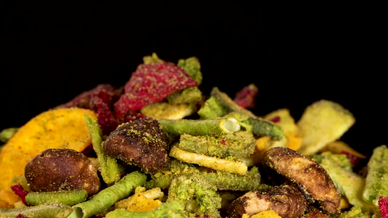 Colorful dried vegetable chips rotate under studio lighting, revealing crispy textures and vibrant details
