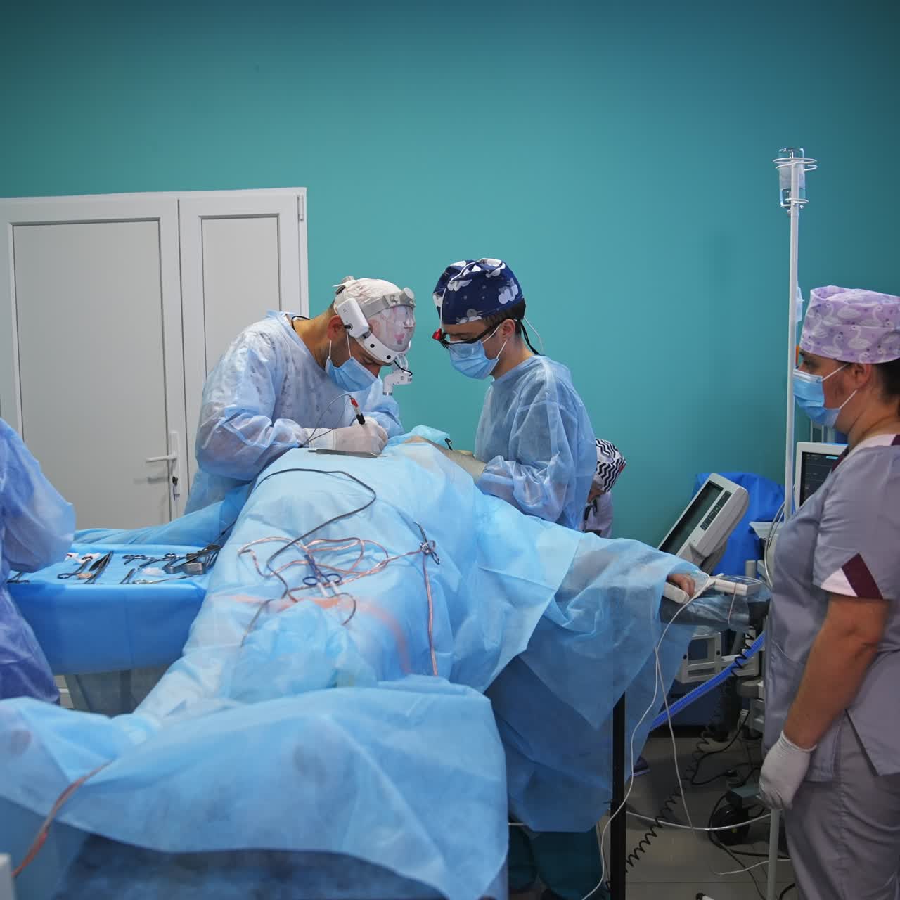 Operational table with a patient in the centre of the surgery room. Team of doctors performing the operation using tools