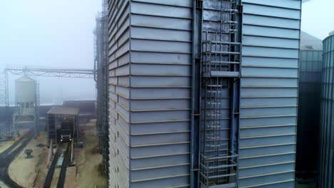 high metal rectangular premise emitting thick grey smoke. going up along the one of the constructions at modern silo complex.