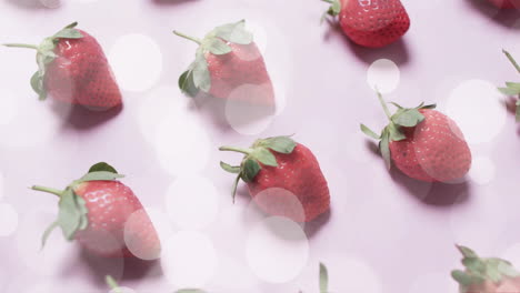 composition of spots of light over strawberries on pink background