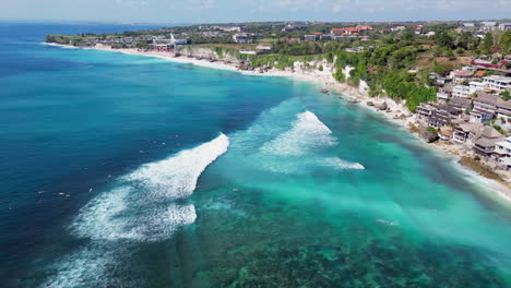 uluwatu limestone cliffs stretch into the distance as surfers float below