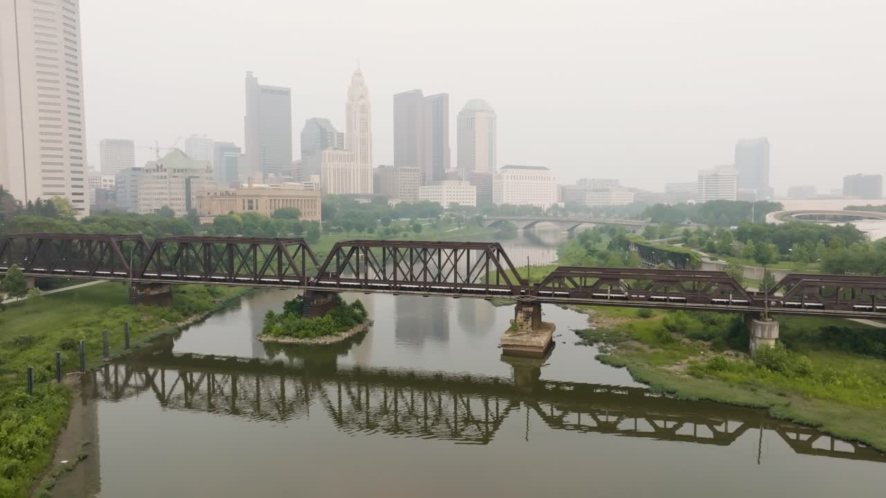 vista aérea del horizonte de columbus, ohio con vías de tren sobre el puente en un día de niebla y humo
