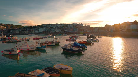 Cinemagraph-seamless-video-loop-of-the-beach-and-harbor-promenade-of-the-famous-town-St-Ives-in-Cornwall-in-Southern-England,-UK-with-fishing-boats-moving-in-the-clear-blue-water-by-sunset