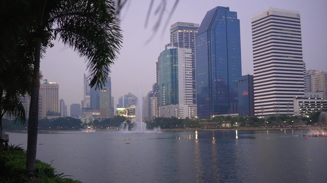 vista del parque benjakitti de los rascacielos a través del lago en la ciudad de bangkok, tailandia dolly de gran ángulo en