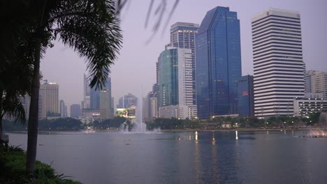 benjakitti park view of skyscrapers across the lake in the city of bangkok, thailand wide angle dolly in