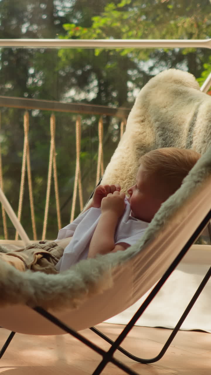 niño pequeño sentado en una silla acogedora frente a la hermana examina cuidadosamente los paisajes montañosos y el bosque fuera de la ventana de glamping. apartamentos de lujo en la naturaleza con montañas para vacaciones familiares