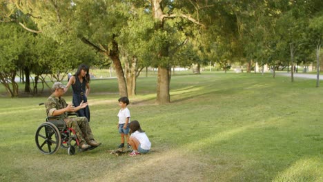 padre militar discapacitado ayudando a los niños con troncos al aire libre