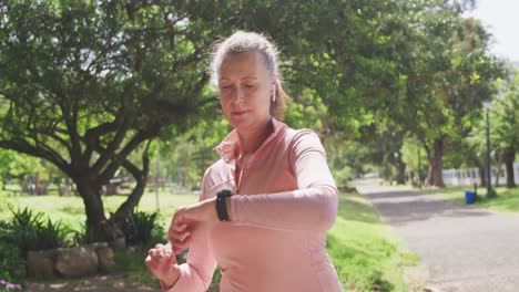mujer mayor usando reloj inteligente en el parque