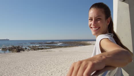 young woman sitting on a beach smiling