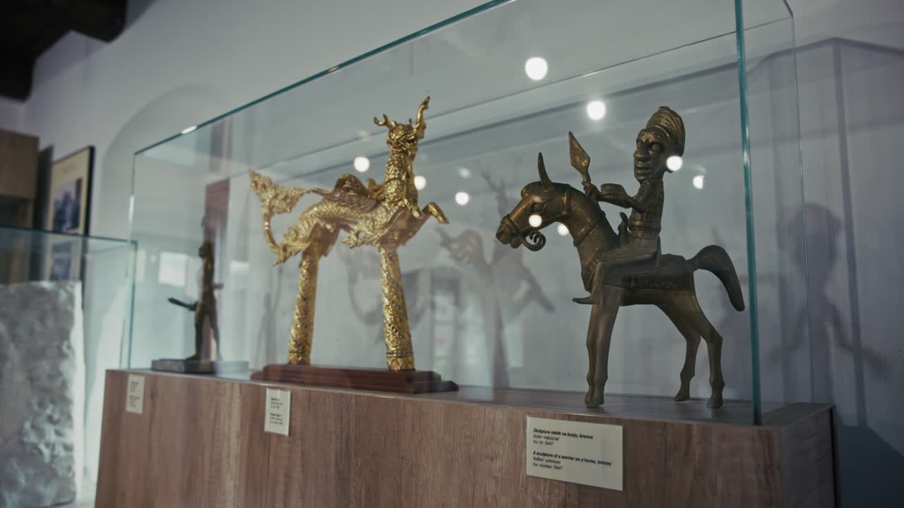 Display of intricate bronze and gold figurines in a glass case at Kumrovec museum, Croatia