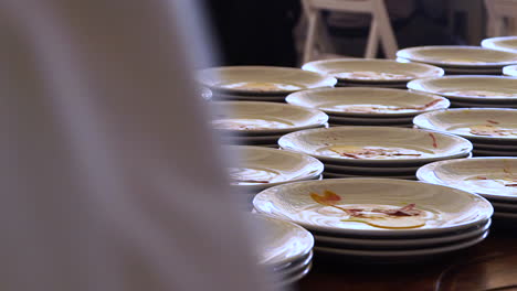 dishes with plating sauce being prepared for a banquet, medium shot pan left