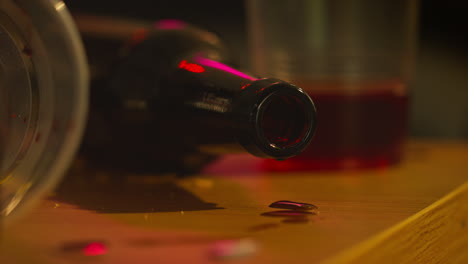 close up of empty wine and bottle dripping on table after house party