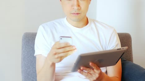 디지털 태블릿과 휴대폰을 사용하는 남자가 거실 4k