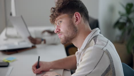 man writing at desk in office
