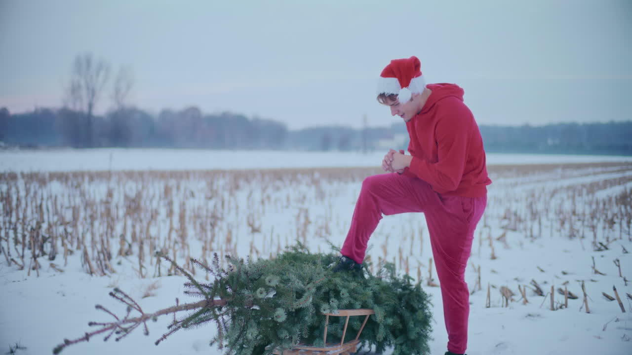 hombre frotando las manos con el árbol de navidad en el paisaje cubierto de nieve contra el cielo
