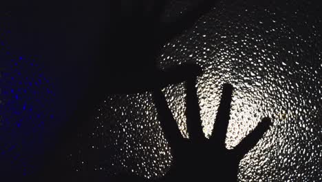 la mano helada de un hombre poseído se arrastra y se arrastra por el vidrio en la oscuridad bajo la luz parpadeante, enviando escalofríos por la columna vertebral