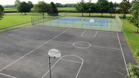 aerial reveal of basketball court and tennis courts at school playground, athletics and sports theme in rural america