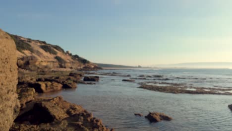 Rotating-view-of-the-rugged-stone-and-rocky-formations-that-embellish-the-seascape-backdrop,-captured-in-the-evening-glow-of-low-angle-sunshine