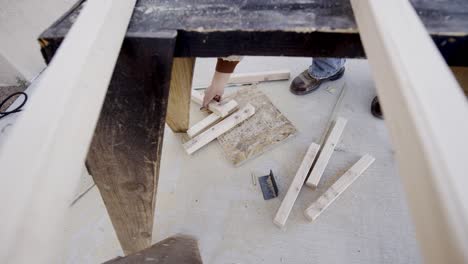 male hands pick up wood scraps or off cuts from workshop floor